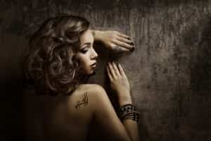Woman leaning against wall with Tattoo shoulder