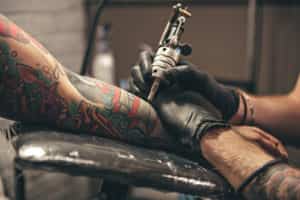 A man getting a forearm tattoo in a tattoo parlor.