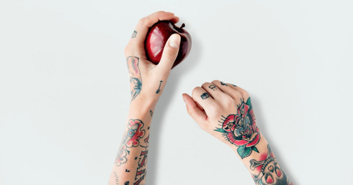 Tattoes arms holding an apple