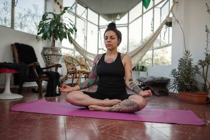 Woman with tattoos exercising yoga at home