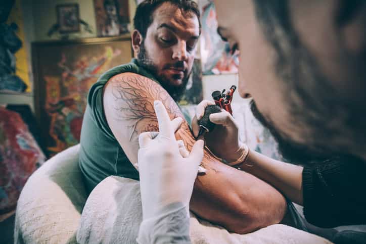 man experiencing pain while getting tattoo
