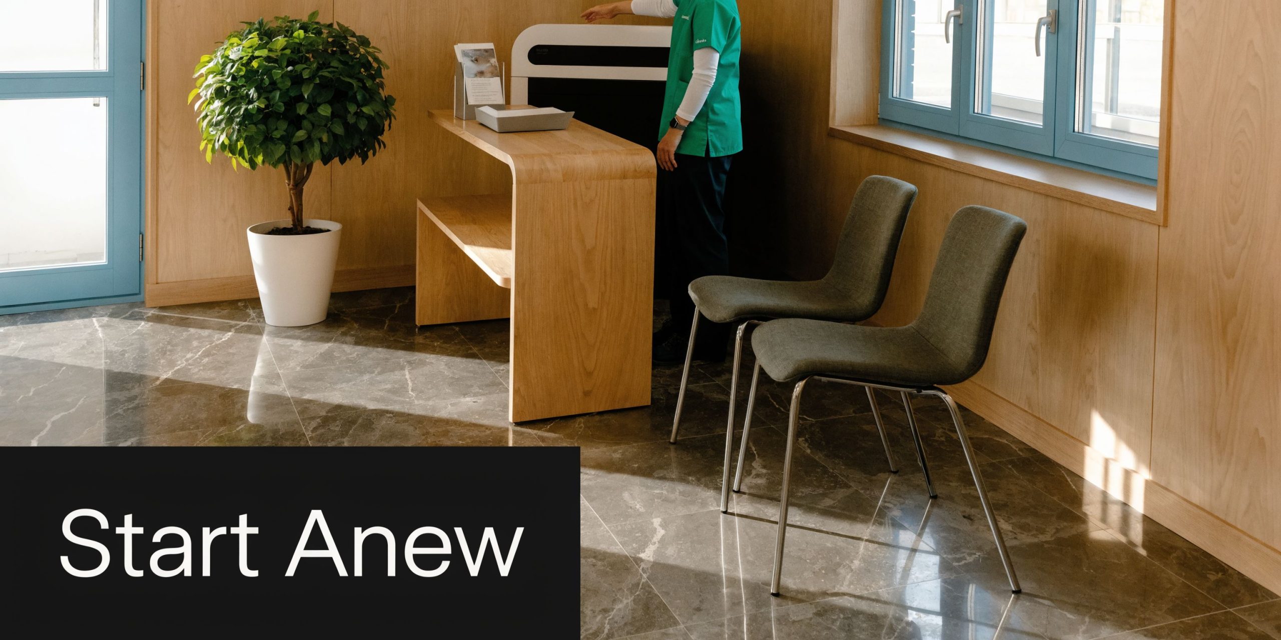 A professional clinic waiting area with wooden reception desk, chairs, and a person in scrubs.