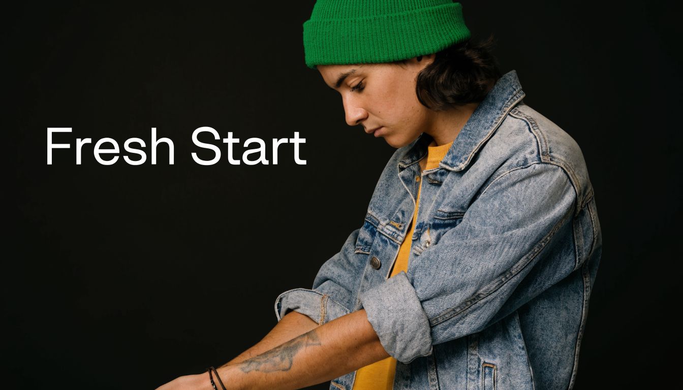 A young person with a green beanie looking down at their arm, contemplating laser tattoo removal options.