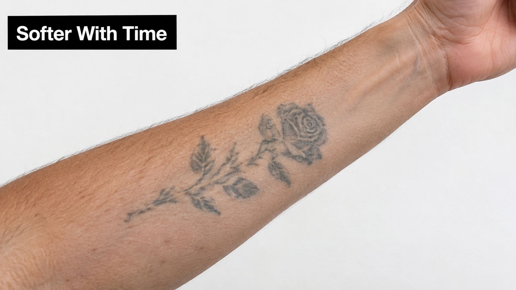 A close-up view of a forearm showing a faded rose tattoo showing how ink softens over time.